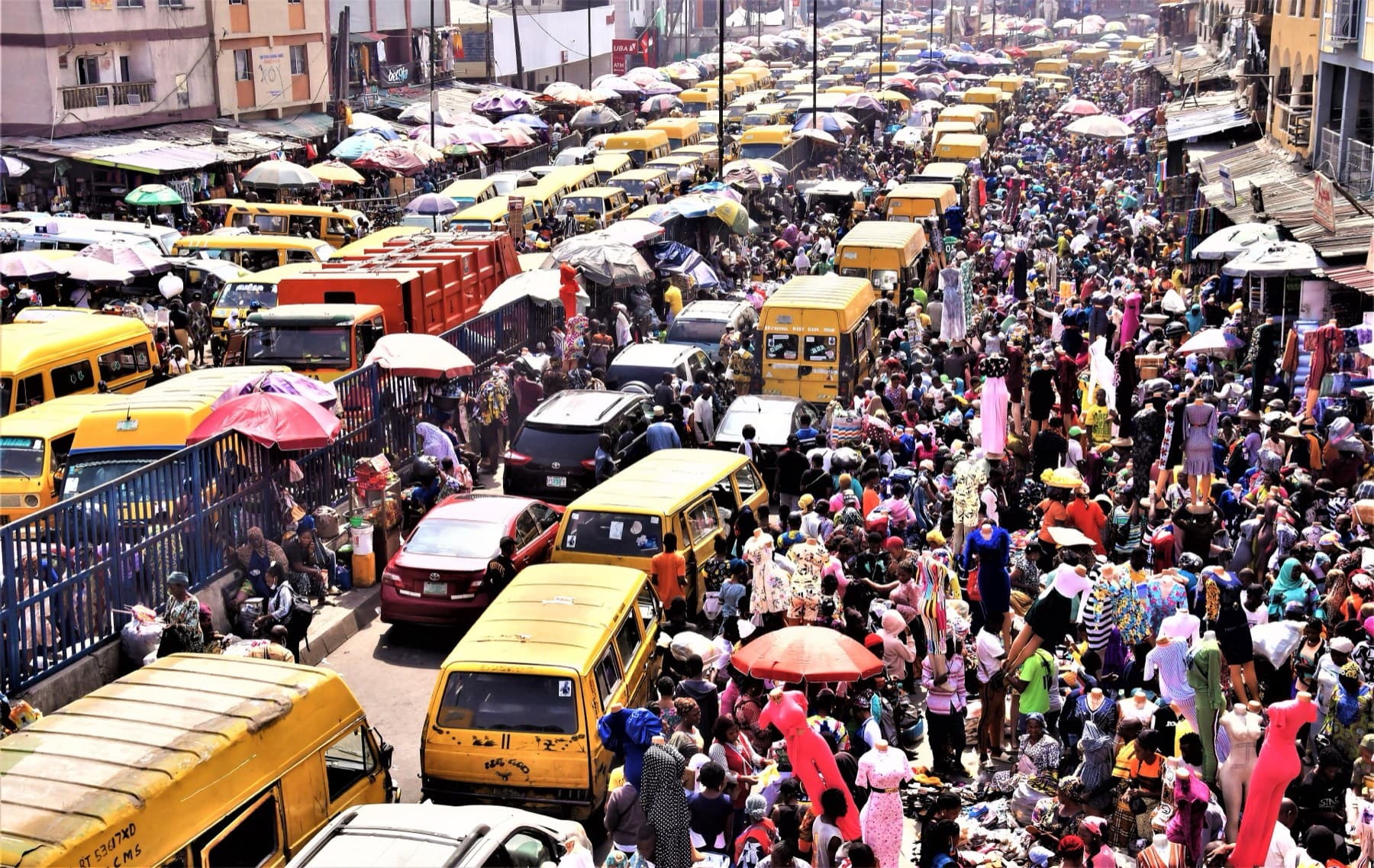 A crowded street at Idumota Market in Lagos, packed with traders, shoppers and yellow danfo buses.